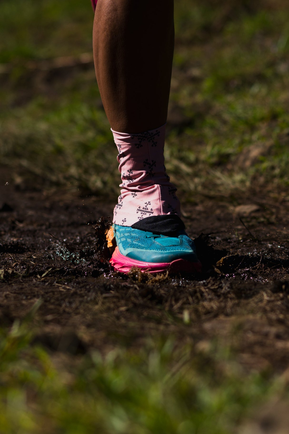 Trail runner in motion wearing Apo 1 Gaiters, kicking up mud on a technical trail.