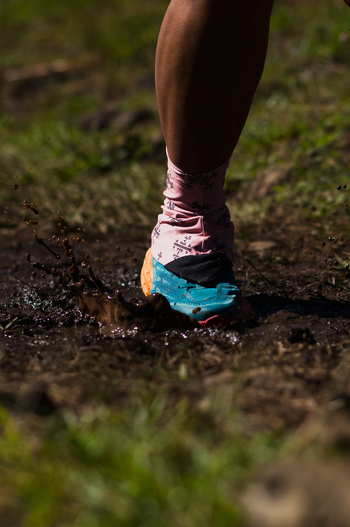 Trail runner in motion wearing Apo 1 Gaiters, kicking up mud on a technical trail.
