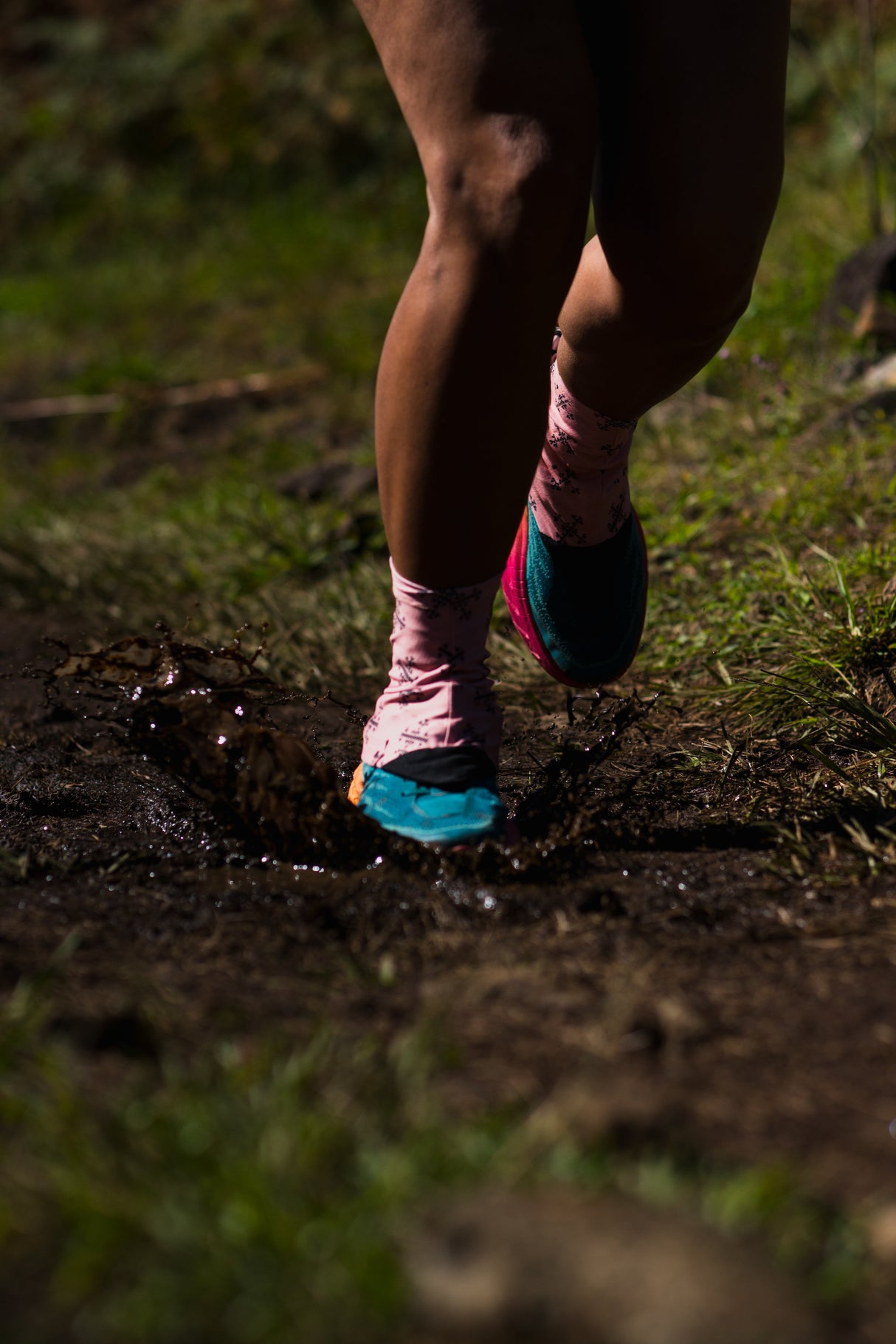 Trail runner in motion wearing Apo 1 Gaiters, kicking up mud on a technical trail.