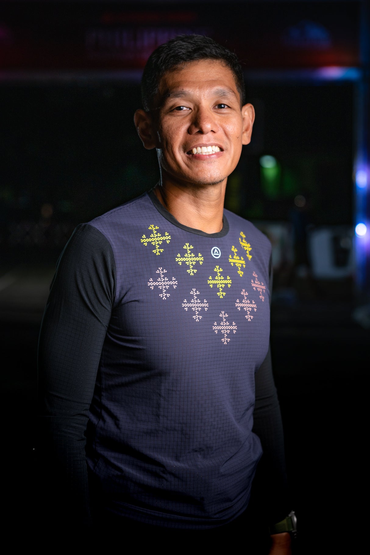 Male ultra trail runner smiling while wearing the Apo Super Light LS Shirt in Dark Purple with printed design