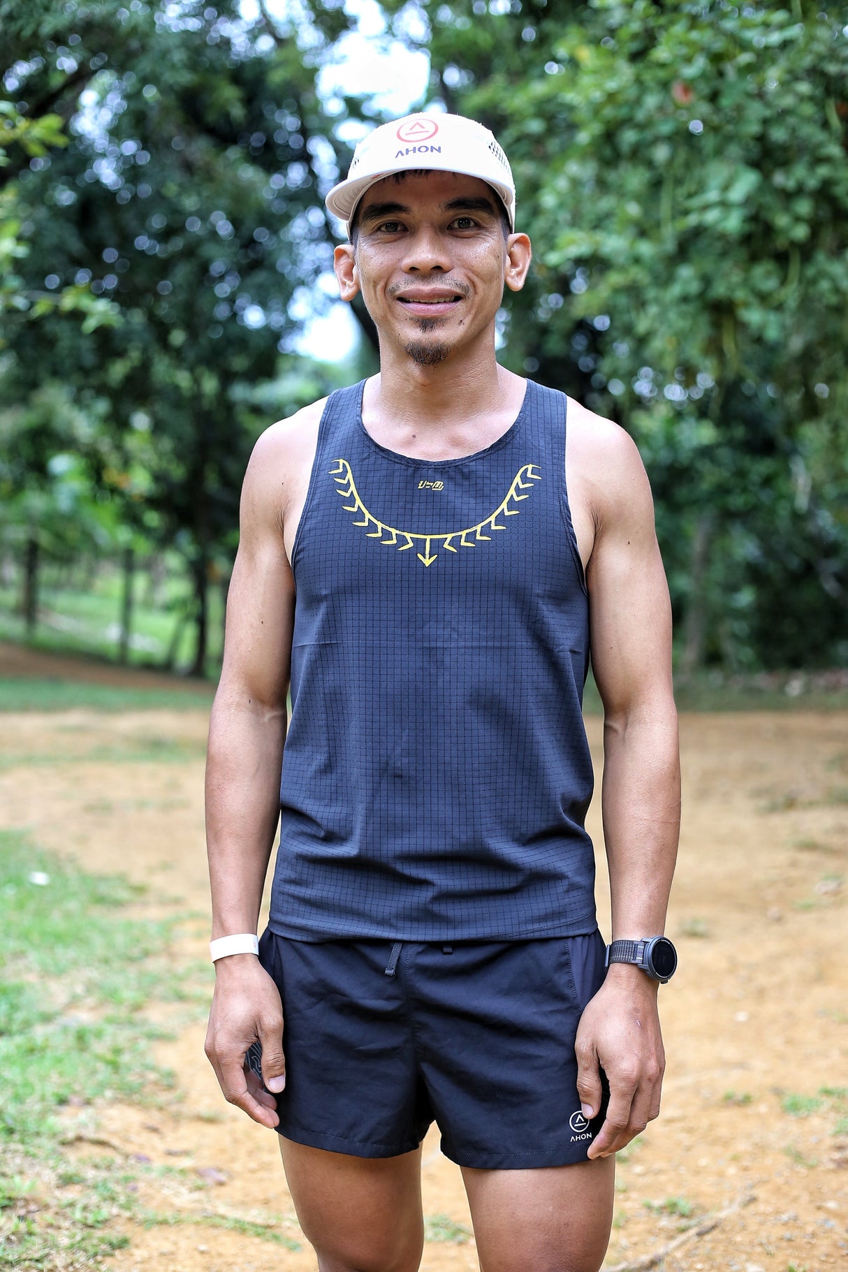 Male trail runner wearing Ahon Koling Super Light Singlet black front, yellow print design