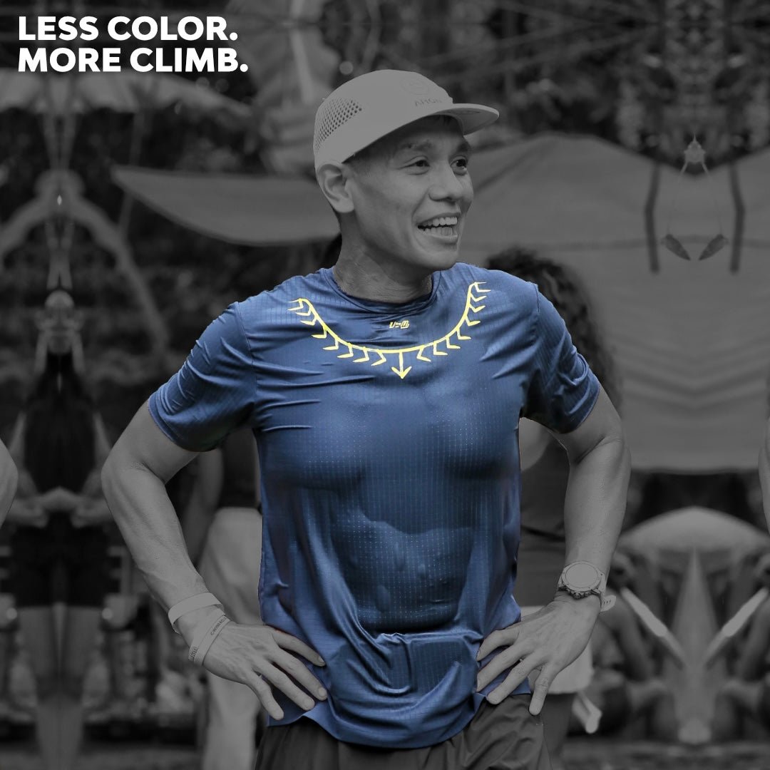 Male trail runner wearing Ahon’s Koling Super Light SS Shirt in black/gray with yellow detail during a mountain race.