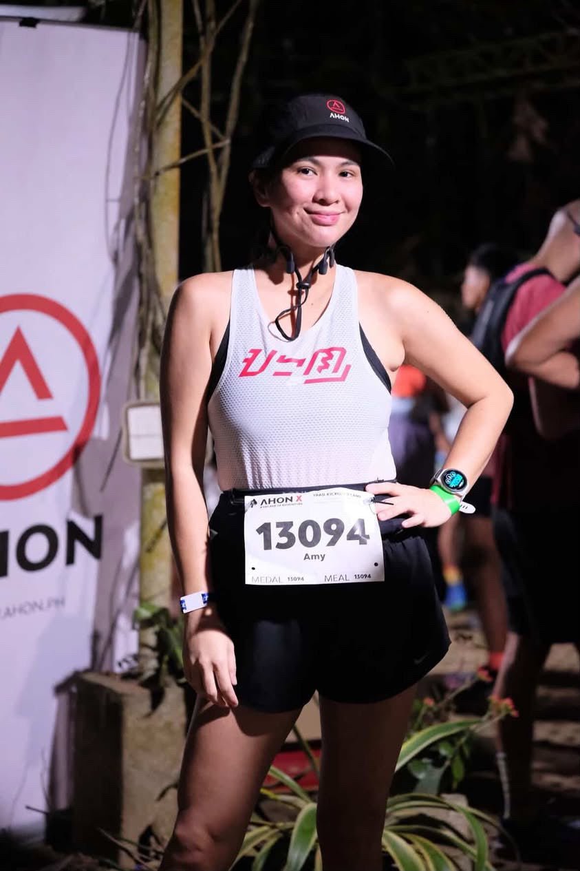 Female trail runner wearing the KSU Singlet 2 by Ahon during a night trail event