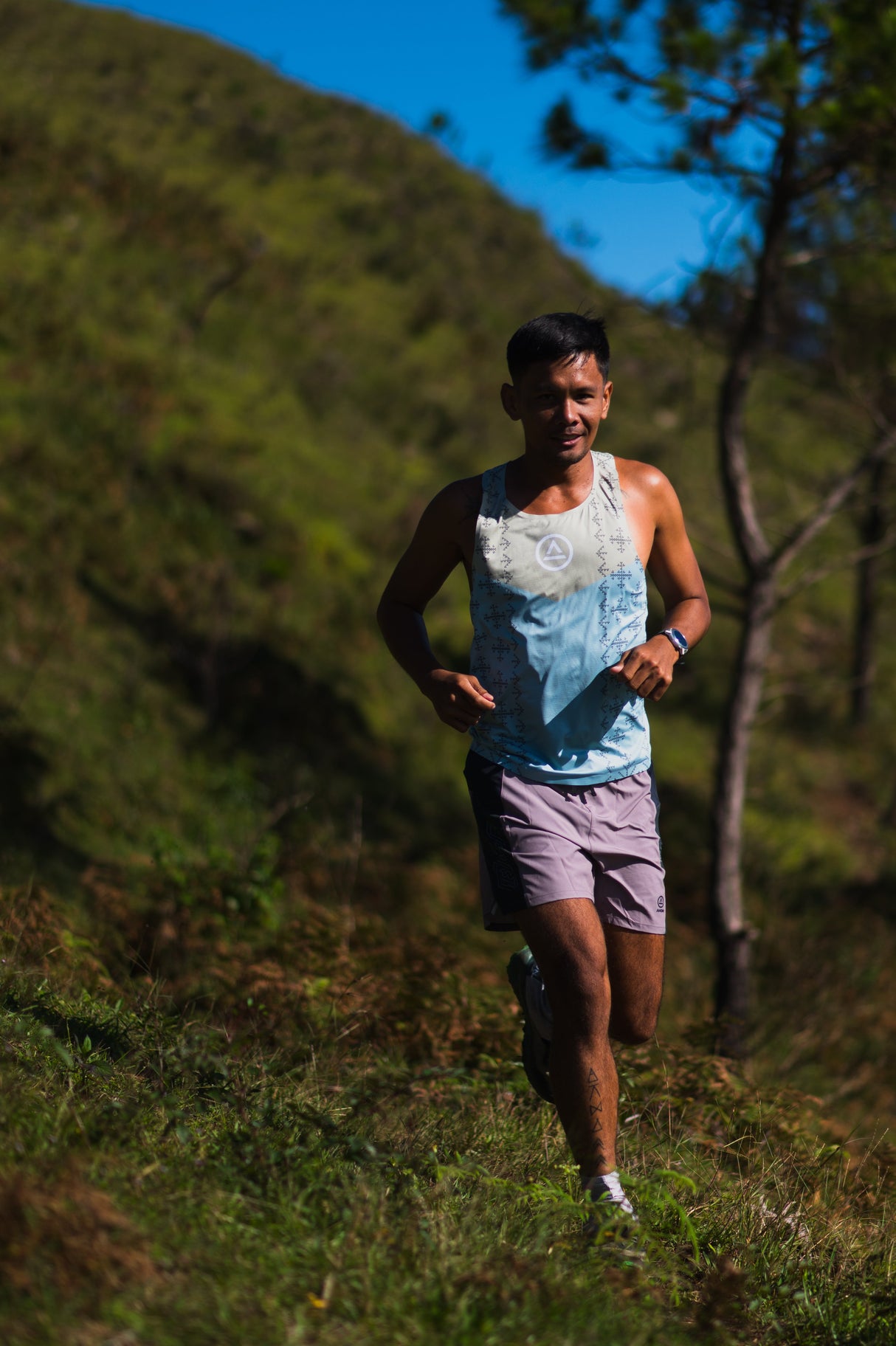 Male trail runner wearing Ahon Singlet Pro Colorway 2, with bold pattern inspired by Bagobo weaving, captured mid-run
