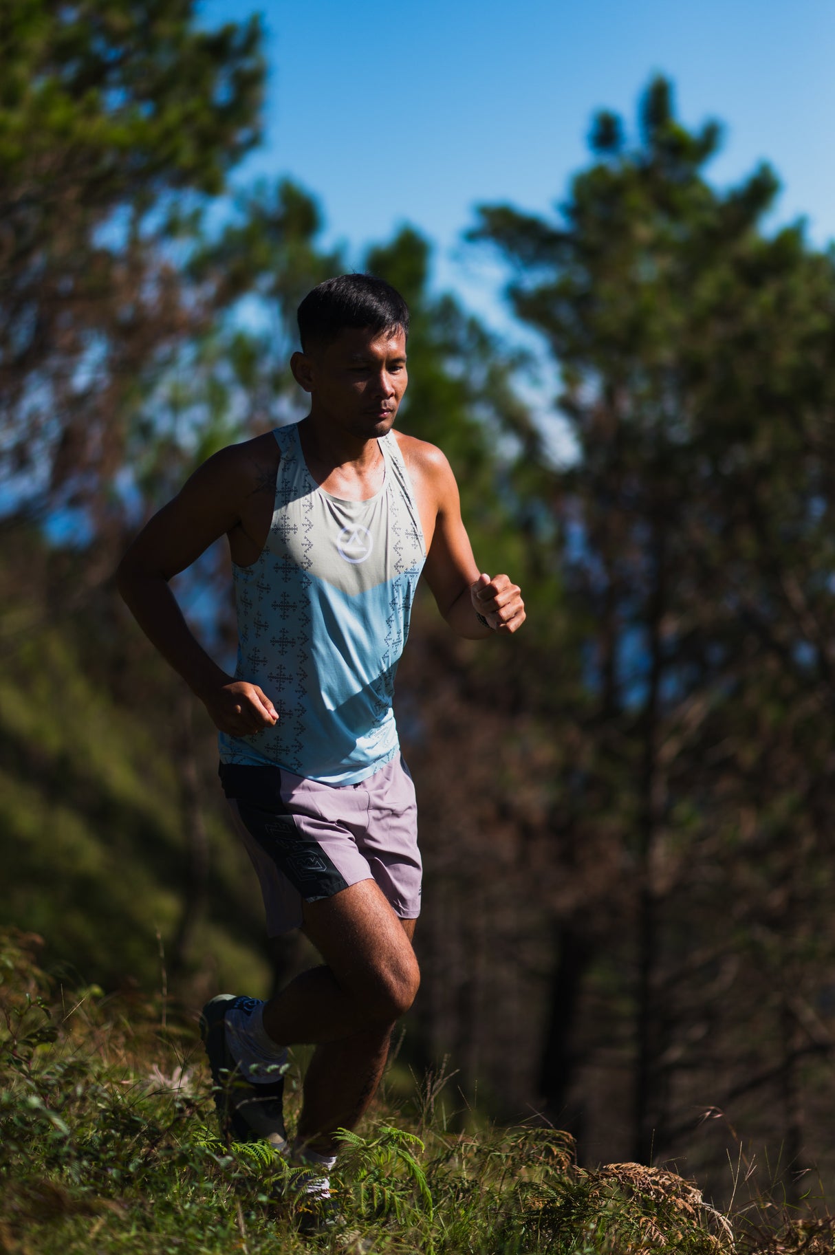 Male trail runner wearing Ahon Singlet Pro Colorway 2, with bold pattern inspired by Bagobo weaving, captured mid-run