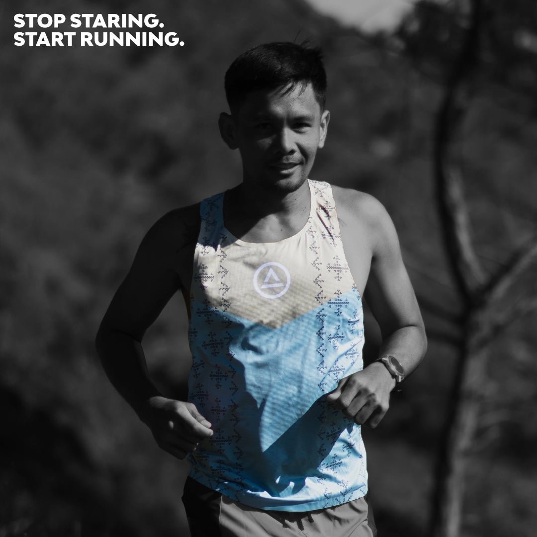 Male trail runner wearing Ahon Singlet Pro Colorway 2, with bold pattern inspired by Bagobo weaving, captured mid-run with the text ‘Stop staring. Start running.’