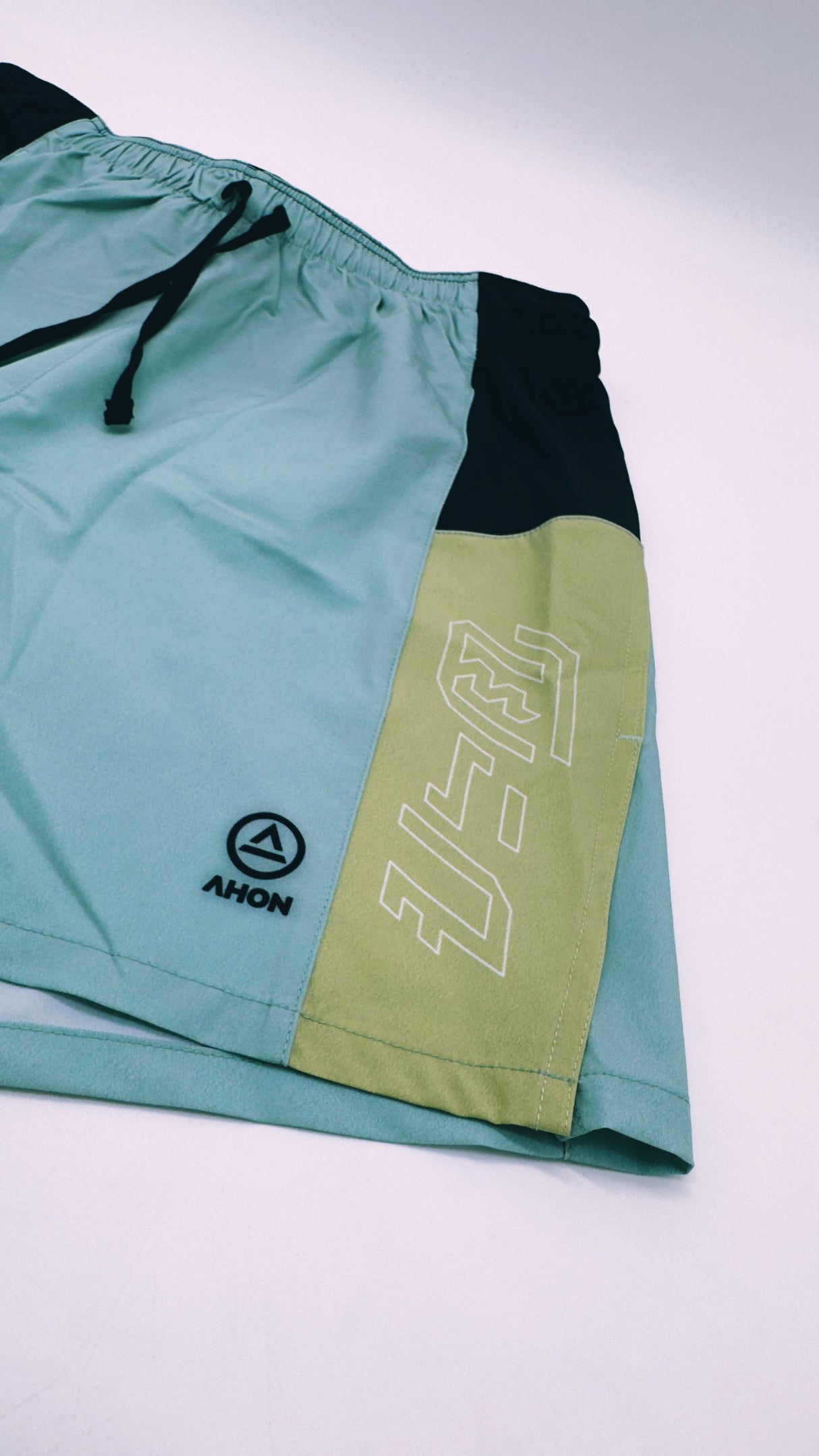 Close-up of Ahon Trail Shorts Pro logo and split side design in Colorway 2