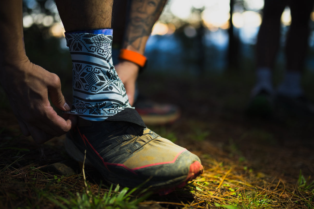 Trail runner wearing Uleyan 2 Gaiters on muddy terrain in forested trail environment