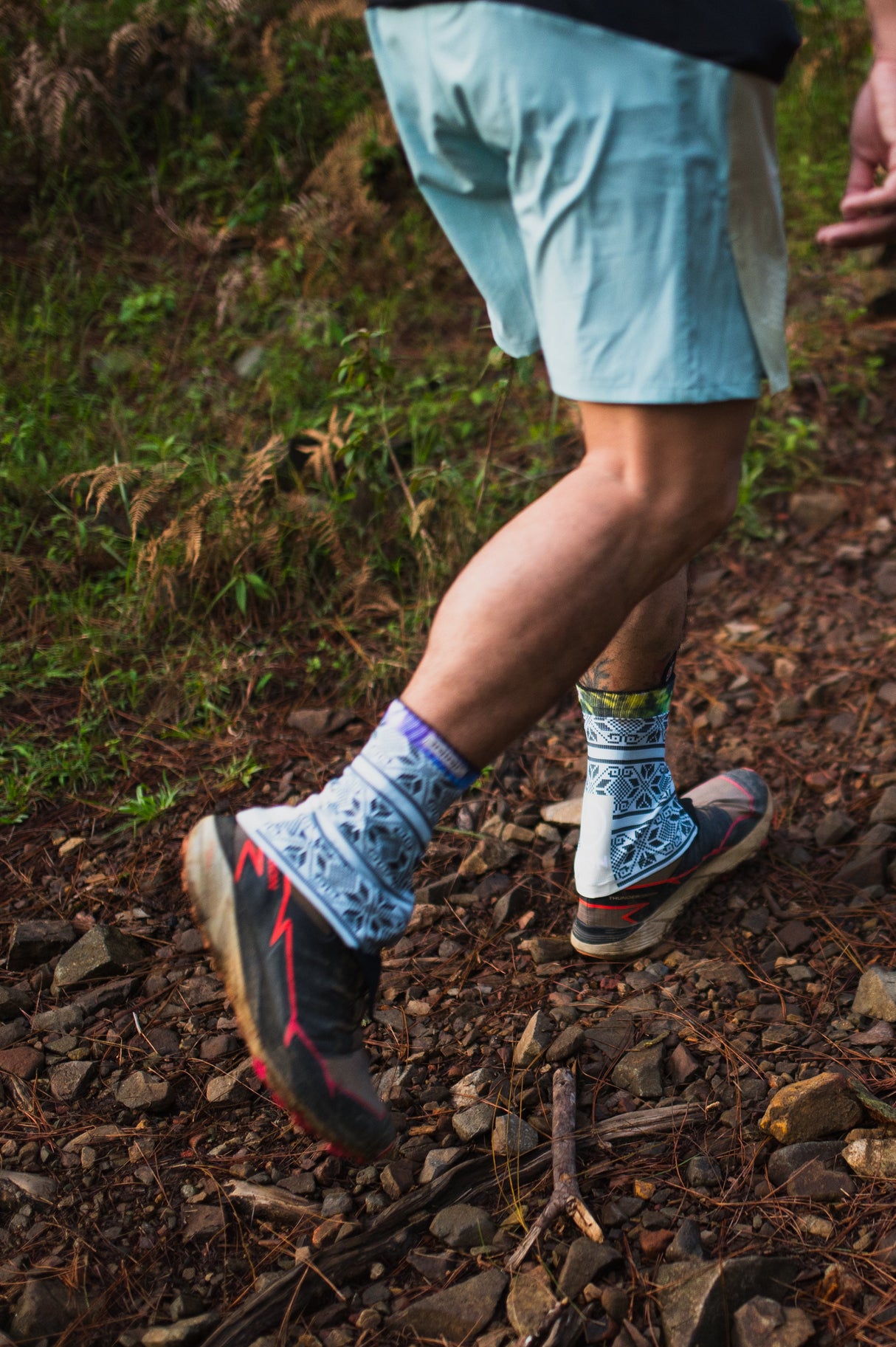 Ahon athlete mid-run through rocky path, showing gaiters in motion