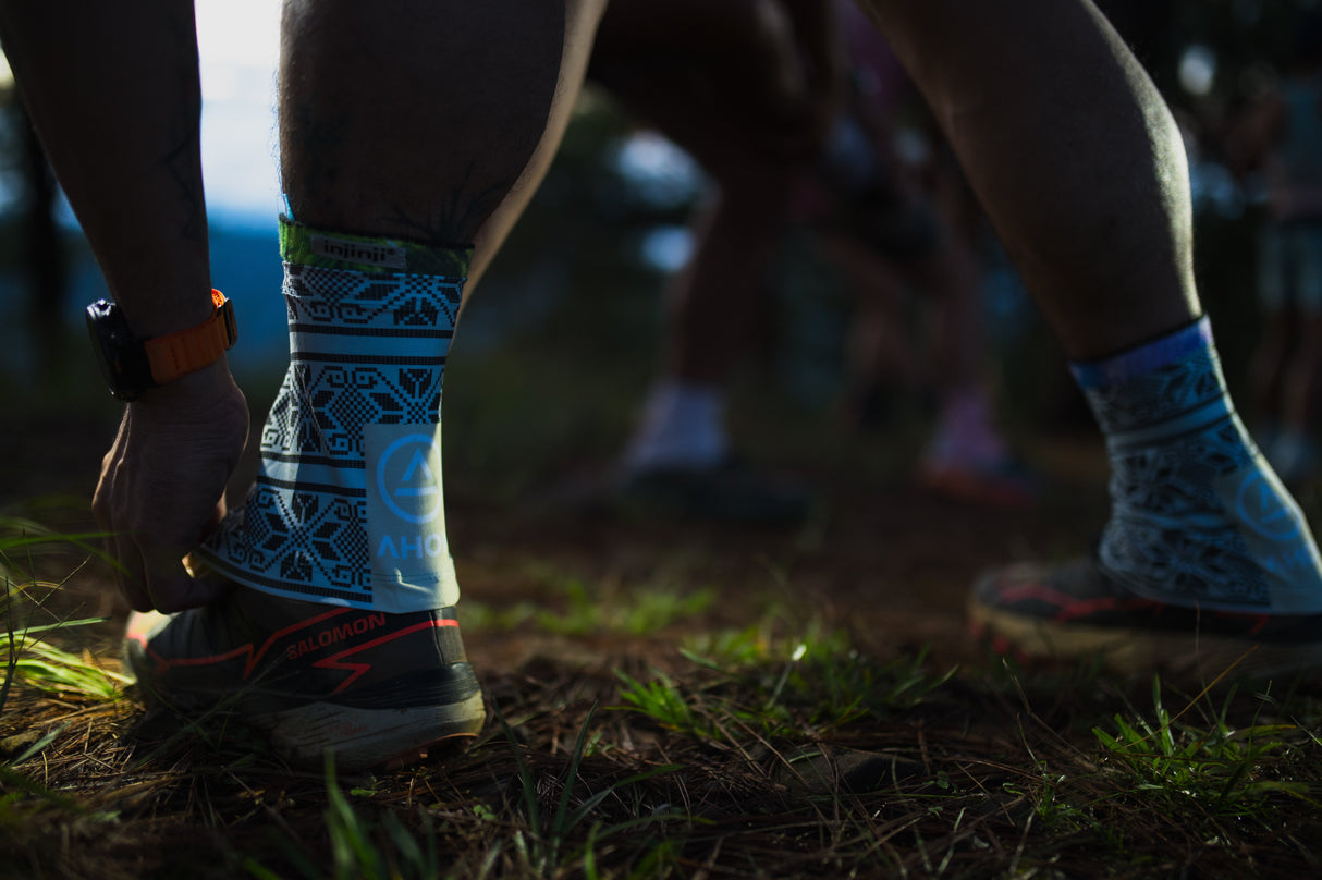 Trail runner wearing Uleyan 2 Gaiters on muddy terrain in forested trail environment