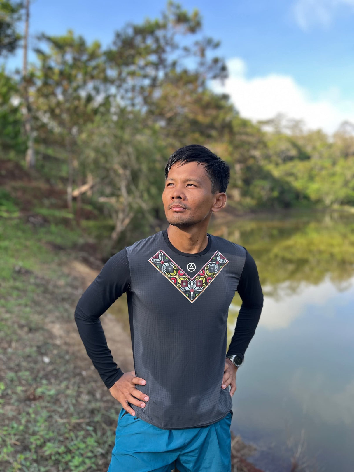 Runner in Uleyan LS Shirt mid-stride on a dirt trail through forested terrain