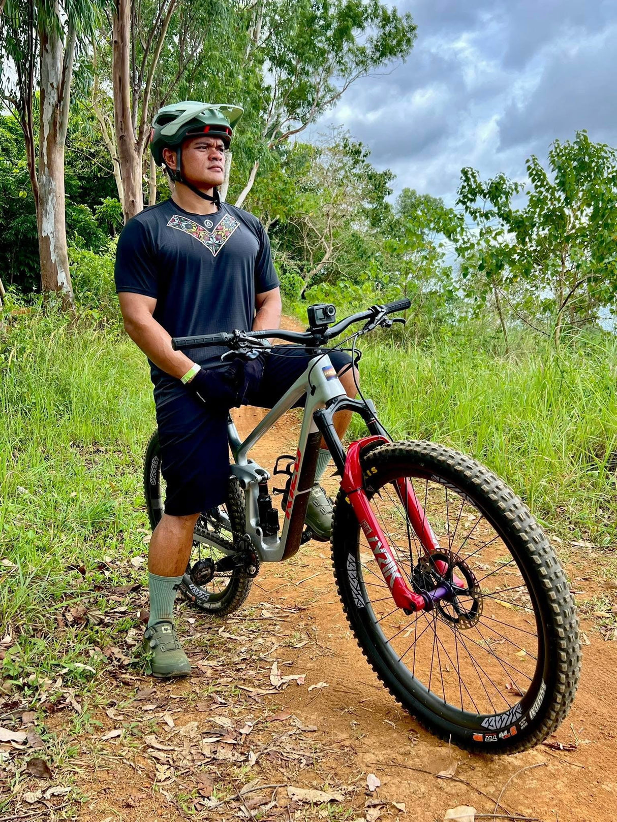 Male mountain biker wearing the Uleyan Super Light SS Shirt in dark gray with colorful woven-inspired chest pattern