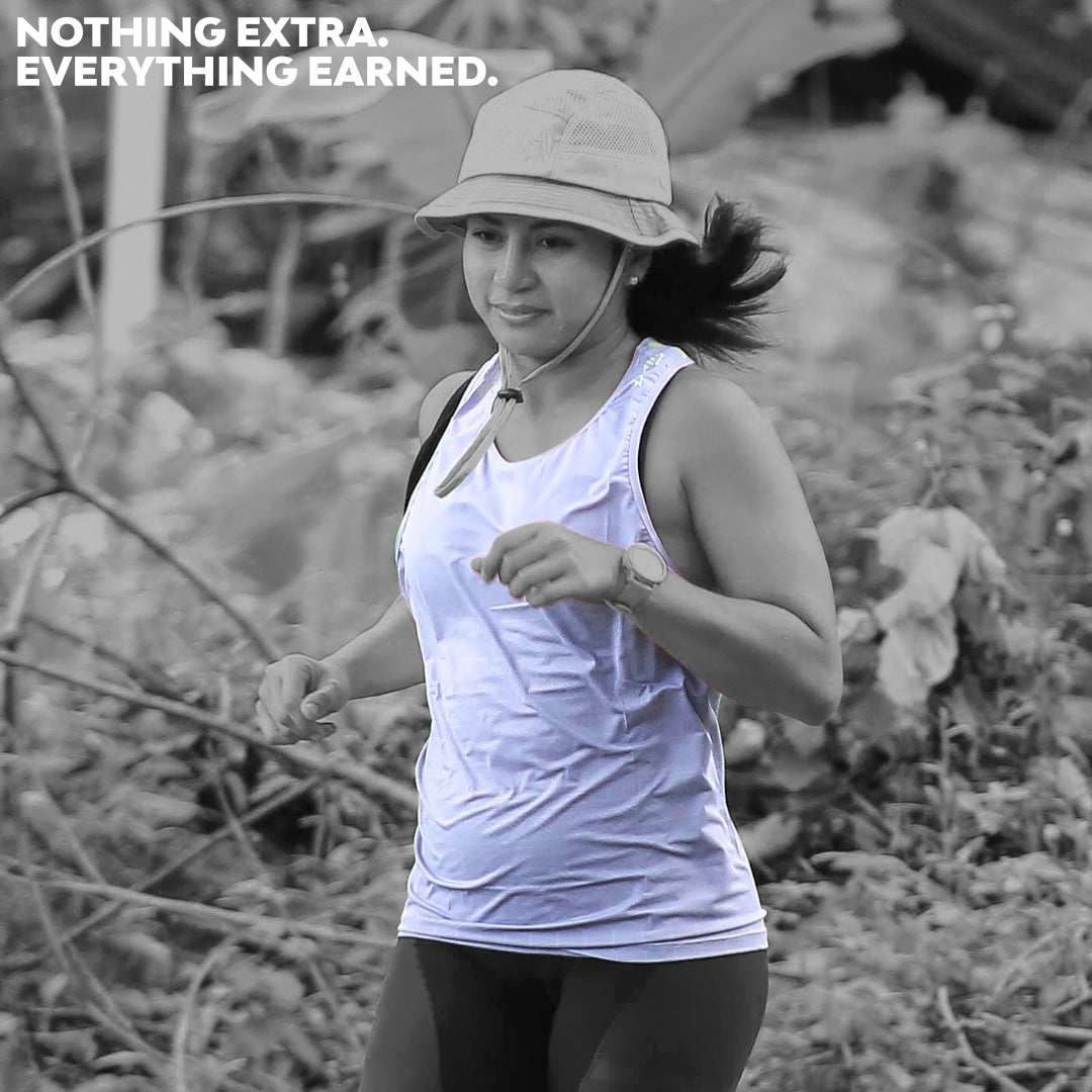 Female trail runner wearing Ahon Ultra Light Singlet in Gray/Yellow with bucket hat on rugged outdoor terrain