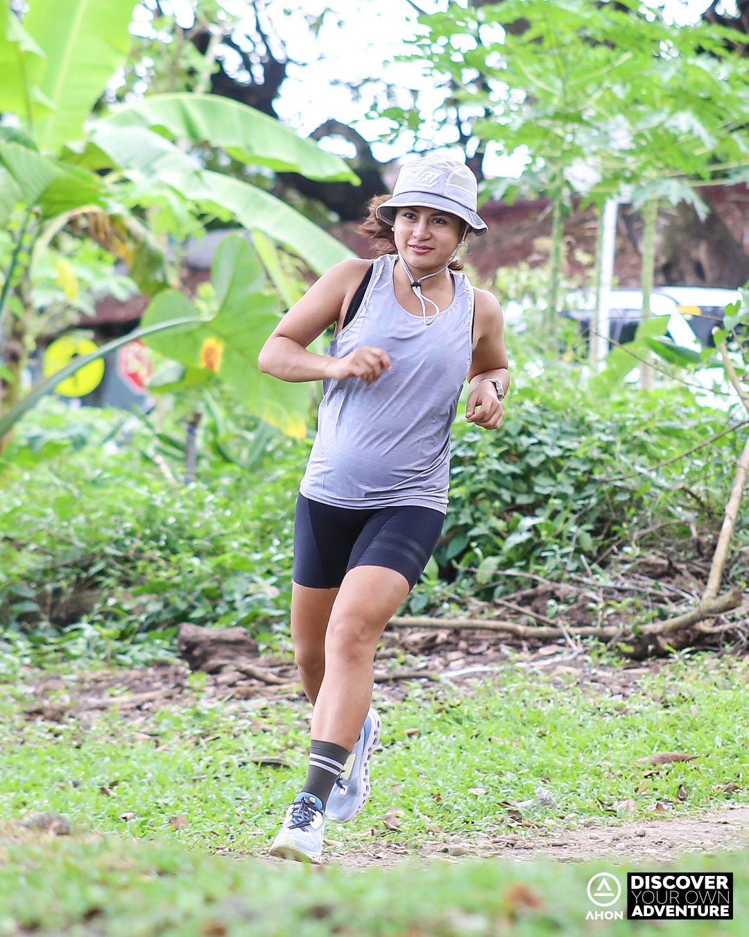trail runner wearing Ahon Ultra Light Singlet in Gray/Yellow with bucket hat on rugged outdoor terrain
