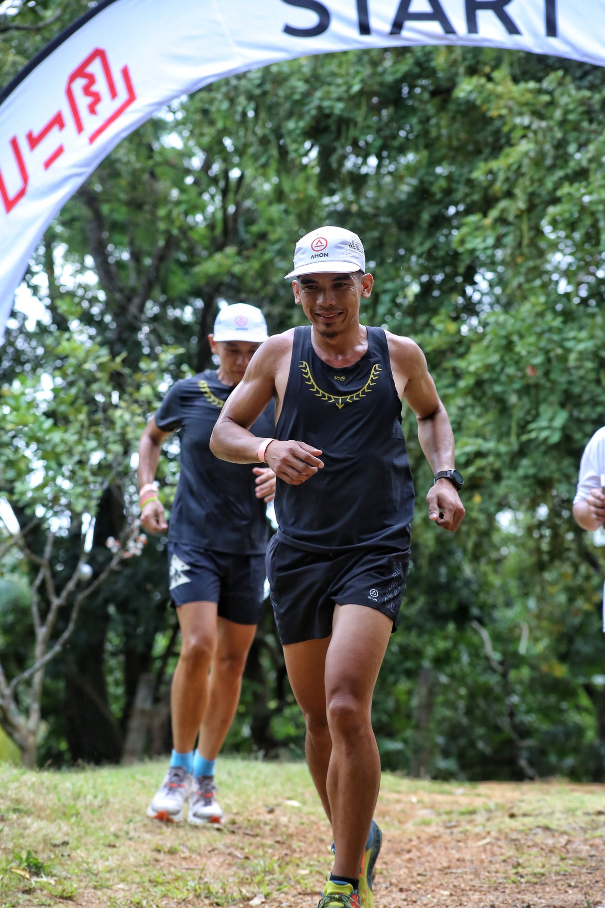 Male trail runner wearing Ahon Koling Super Light Singlet black front, yellow print design
