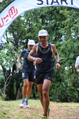 Male trail runner wearing Ahon Koling Super Light Singlet black front, yellow print design