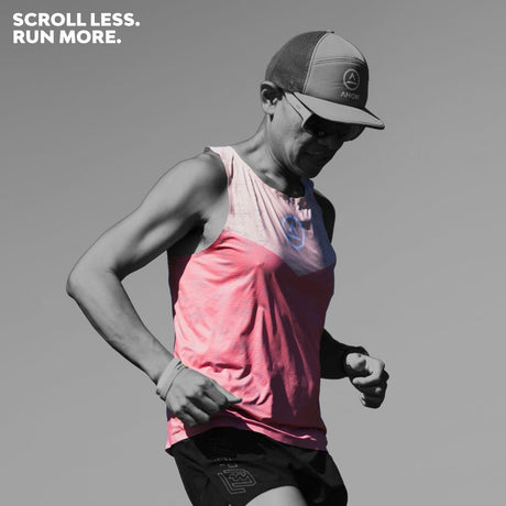 Trail runner wearing red-beige Singlet Pro Colorway 1 with Ahon cap, racing in the sun.