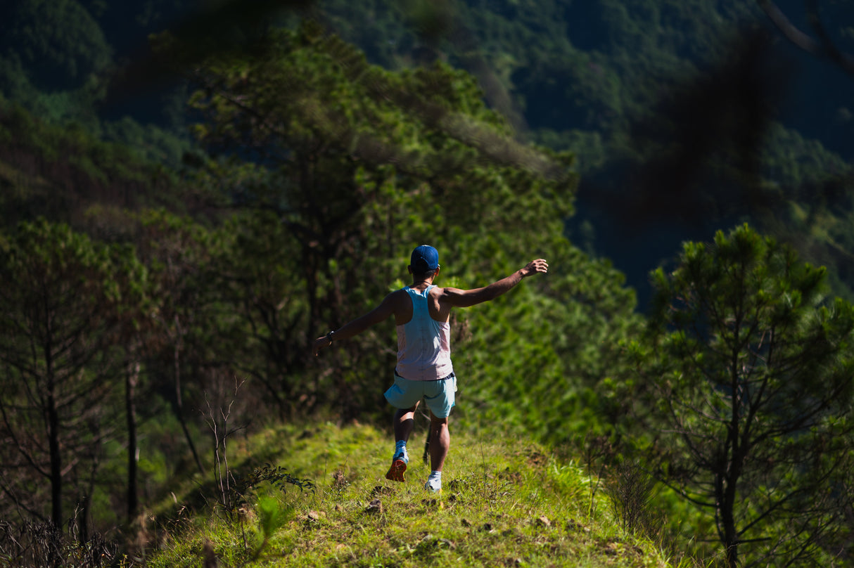 Rear view of Singlet Pro showing racerback cut and color fade. trail runner running down a ridge.